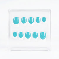 A set of ten press-on nails with a glossy turquoise blue base and french tips, displayed inside a clear acrylic square box on a white background.