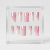A set of 10 square press-on nails displayed inside a clear acrylic square box on a light gray background. The nails feature a pink and white ombre gradient design with delicate white line art and small rhinestone accents.