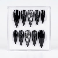Ten black Stiletto press-on nails arranged in two rows inside a clear plastic display case on a white background.