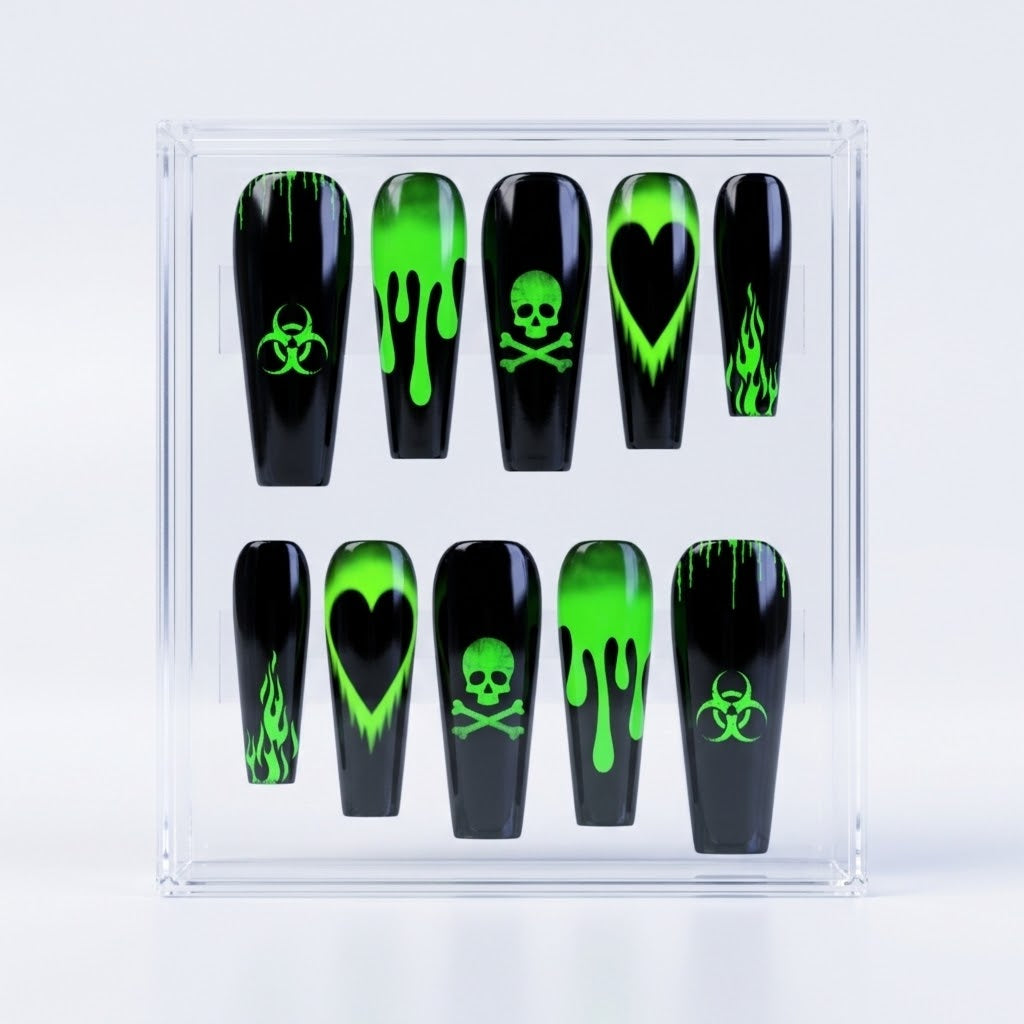A set of ten coffin-shaped glossy press-on nails displayed in a clear acrylic case against a white background. The nails are glossy black with various neon green designs, including dripping patterns, skulls and crossbones, hearts, biohazard symbols, and flames.