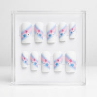 A set of 10 square white glossy press on nails featuring a trans colours themed design. With pink and pale bue ombre swipe and small pink, blue and white flowers with rhinestone centres.