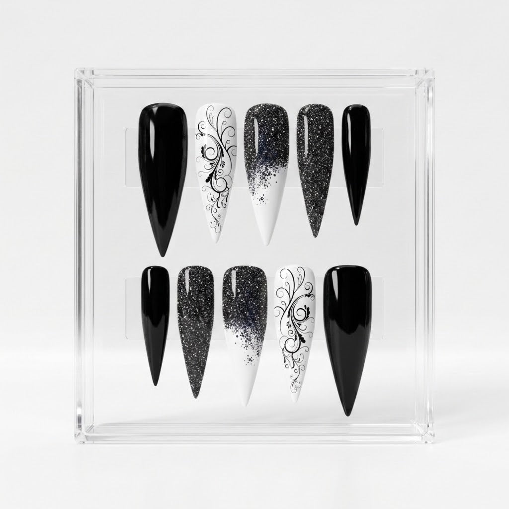 A set of 10 black and white Stiletto-shaped press-on nails displayed in a clear acrylic case against a light gray background.