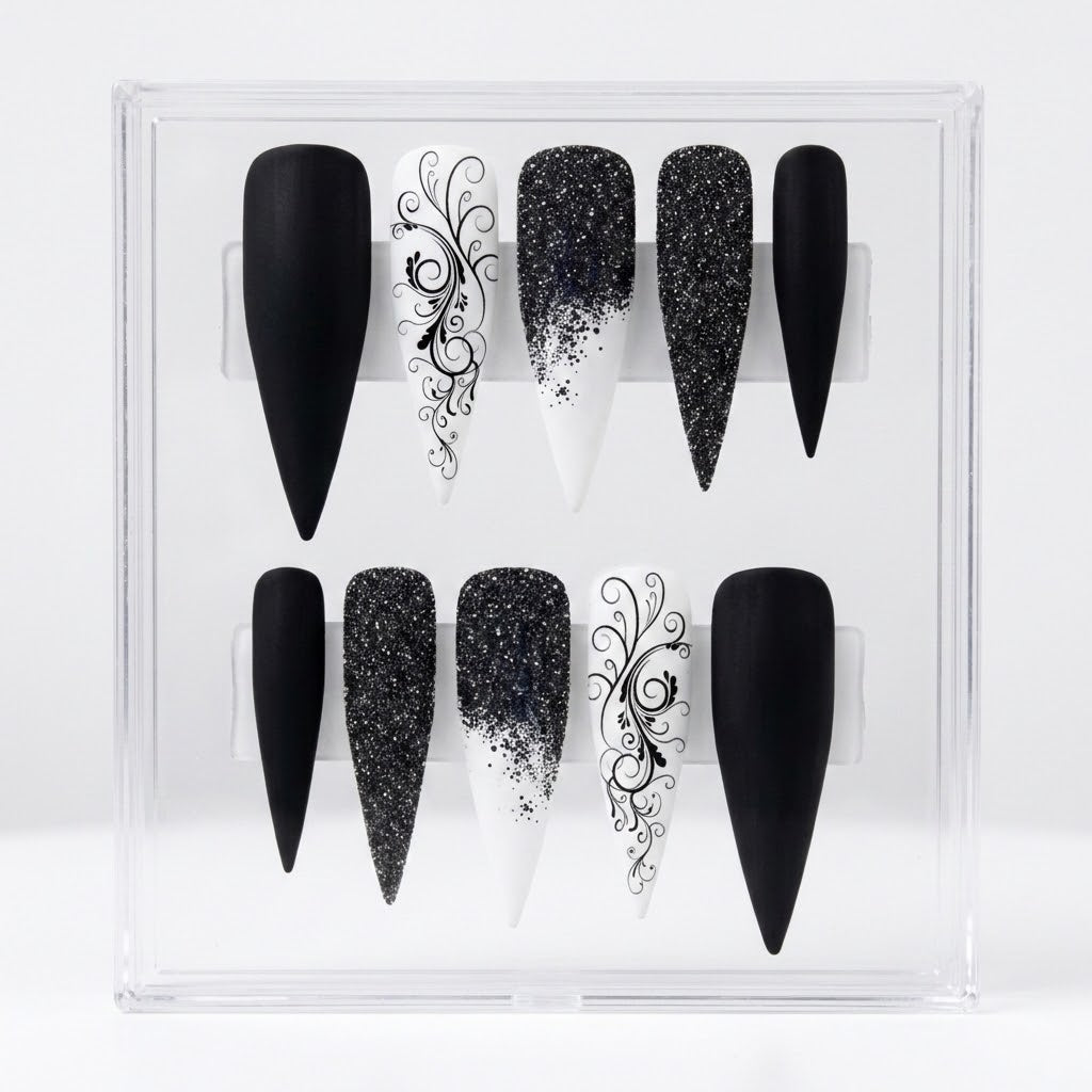 A set of 10 black and white stiletto-shaped press-on nails displayed inside a clear plastic storage box against a white background.