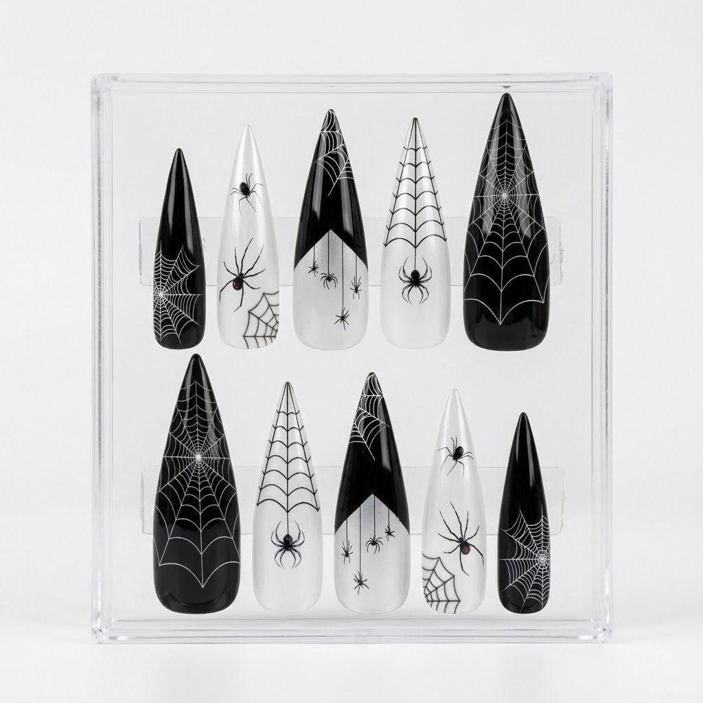 A set of 10 glossy pointed stiletto press-on nails with black and white spider web and spider designs, displayed inside a clear acrylic case on a white background.