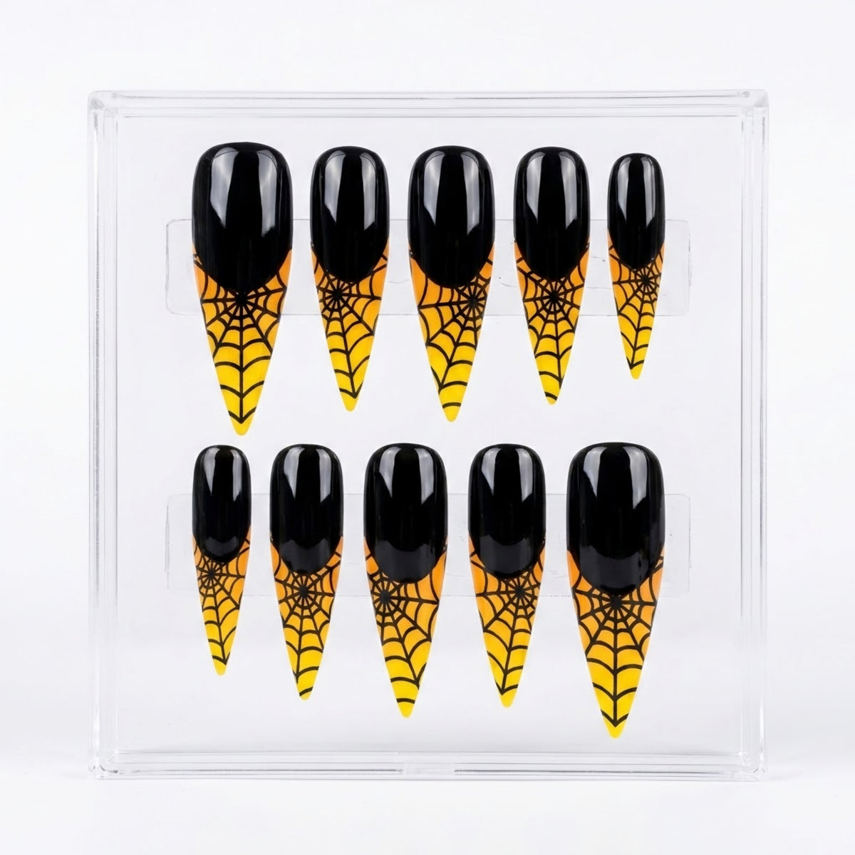 A set of ten stilettos press-on nails with a glossy black base and a yellow spider pattern on the tip, displayed inside a clear plastic case against a white background.