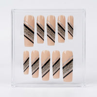 A set of 10 press-on nails displayed in a clear plastic storage box. The nails have a nude beige base with diagonal stripes in black, metallic silver, and a leopard print pattern.
