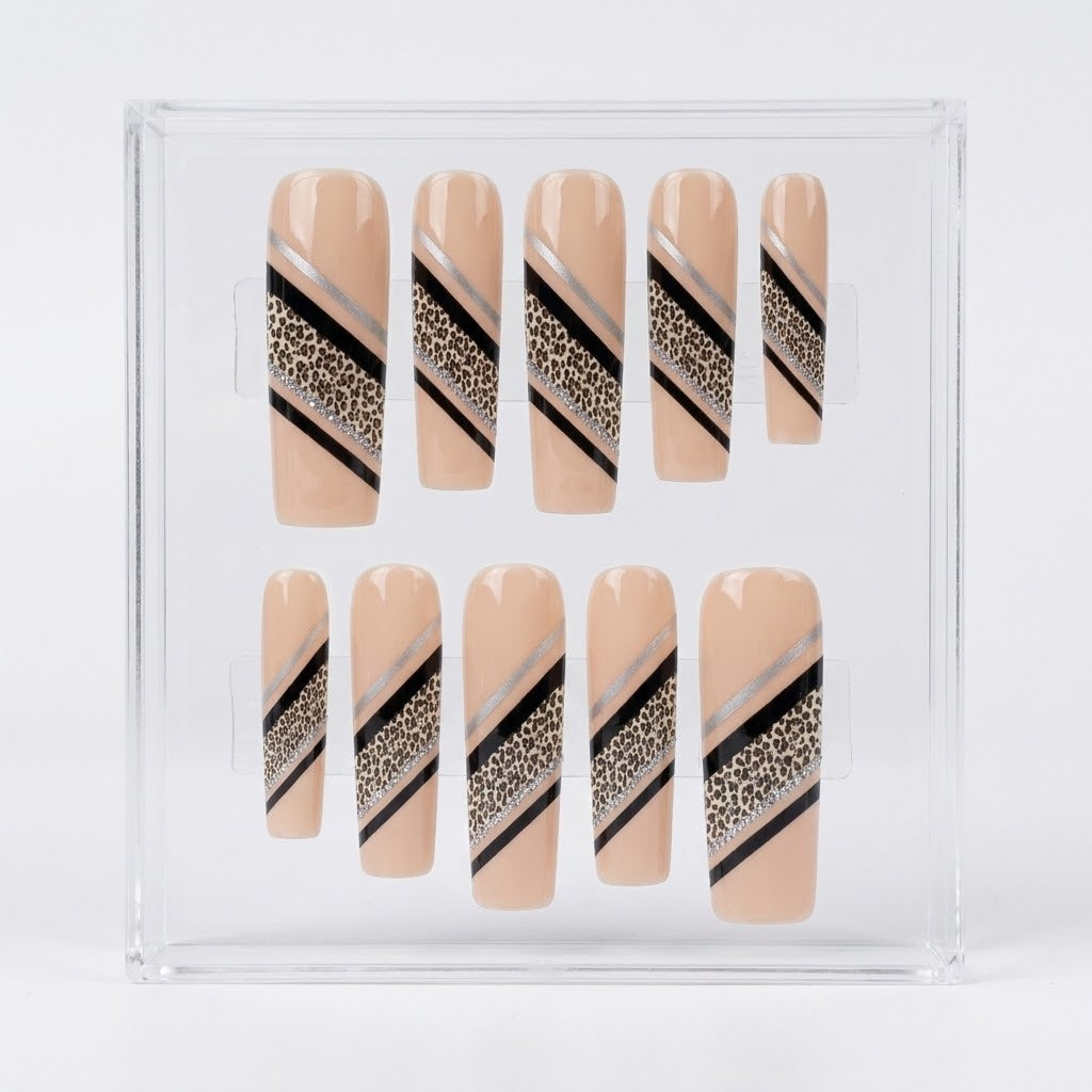 A set of 10 press-on nails displayed in a clear plastic storage box. The nails have a nude beige base with diagonal stripes in black, metallic silver, and a leopard print pattern.