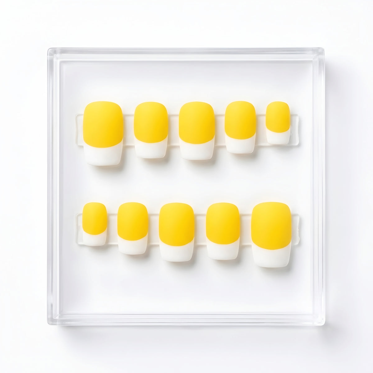 A set of ten press-on nails arranged in two rows inside a clear plastic display box on a white background. The nails feature a bright yellow base and a white french, creating a classic French manicure style.