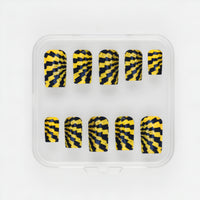 Radioactive yellow and black glow-in-the-dark press-on nails with gold glitter in short square